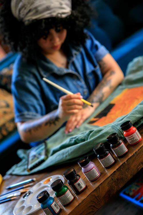 Free Focused woman painting on fabric, displaying artistic talent in a creative studio environment. Stock Photo