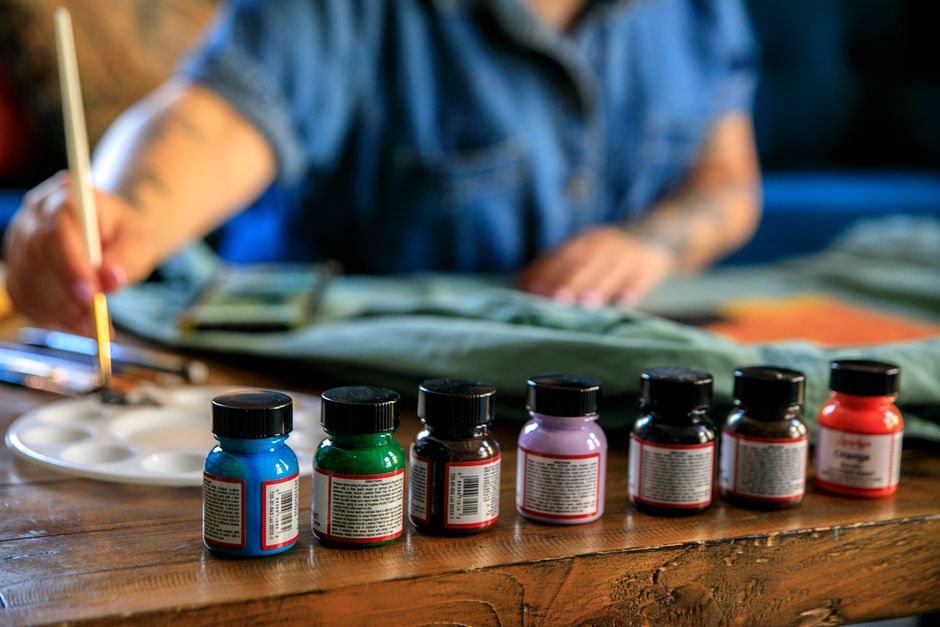 A person painting on a table with a variety of colorful paints, engaging in artistic activity.