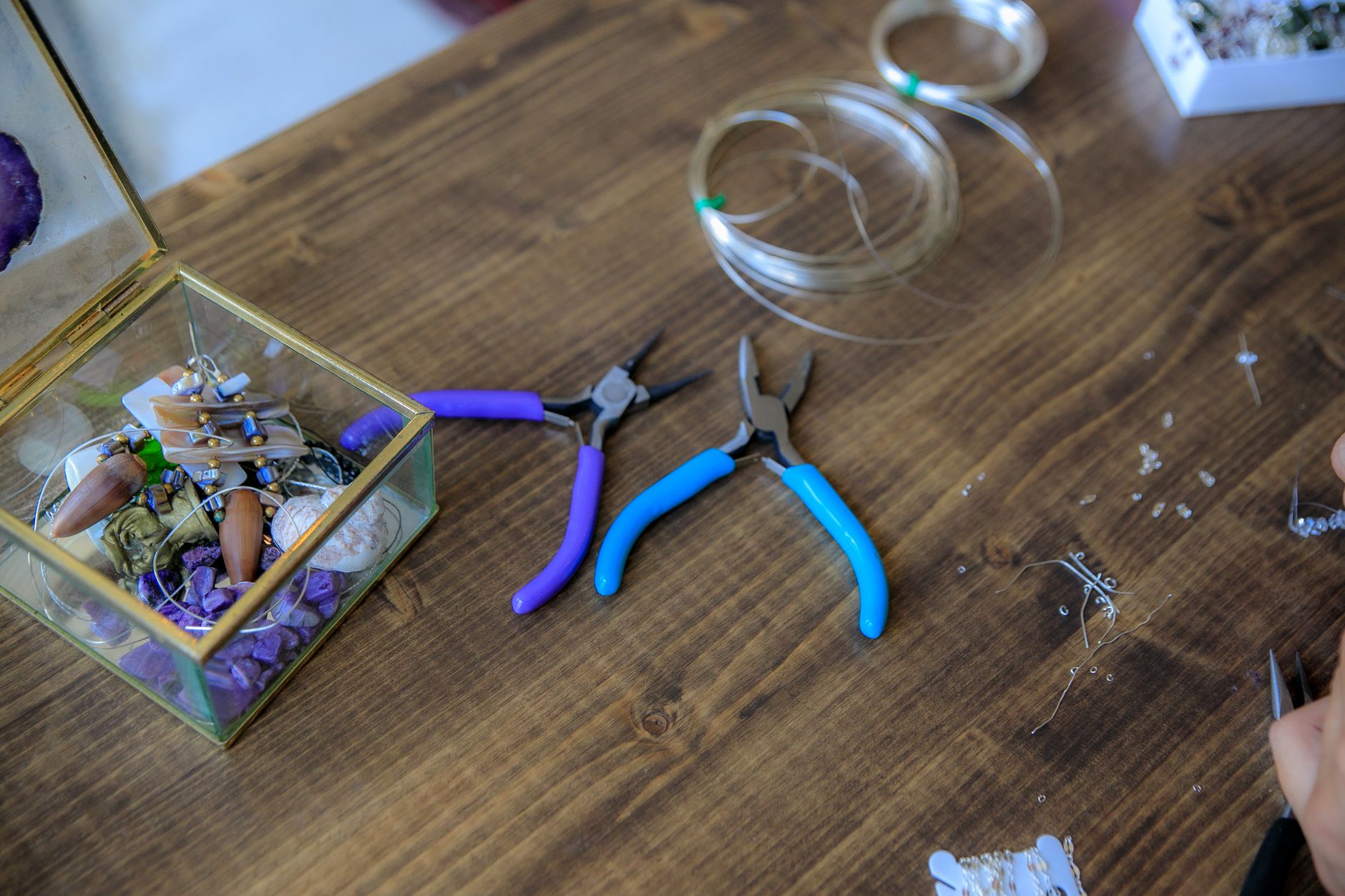 A detailed view of jewelry making tools and materials arranged on a wooden table for crafting.