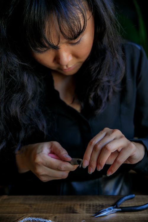 Free Female artisan skillfully making handmade jewelry with tools indoors. Stock Photo