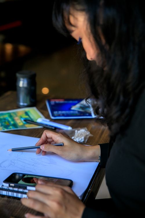 Free Woman with black hair sketching on tablet with pencil in creative studio setting. Stock Photo