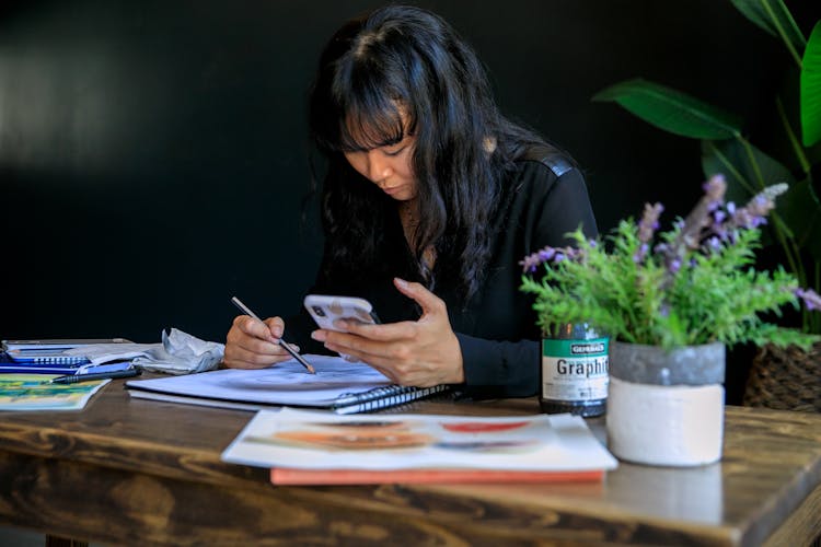 Woman Drawing And Looking At Phone