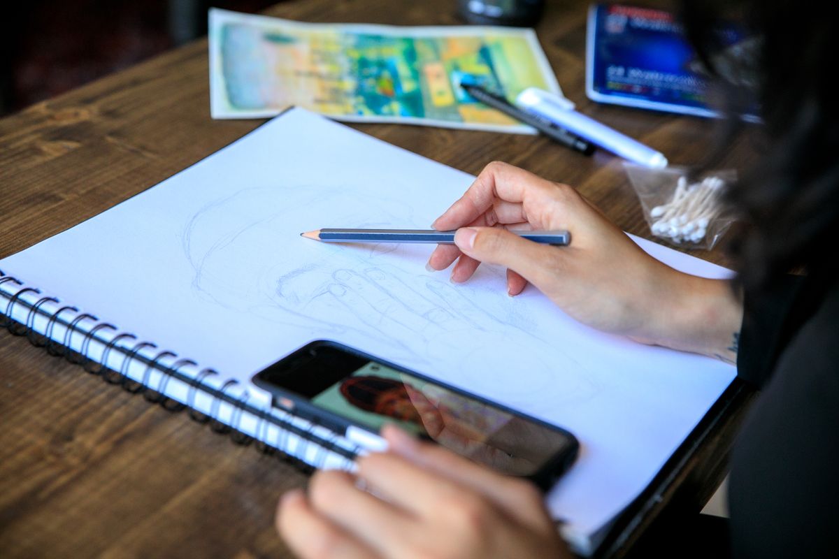 Sketching a shopping app layout with a phone for reference