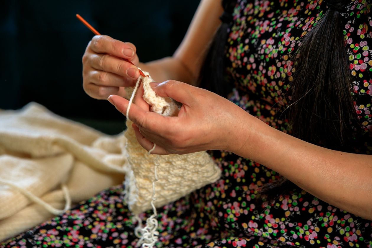 Mãos trabalhando artesanalmente com fio e agulha