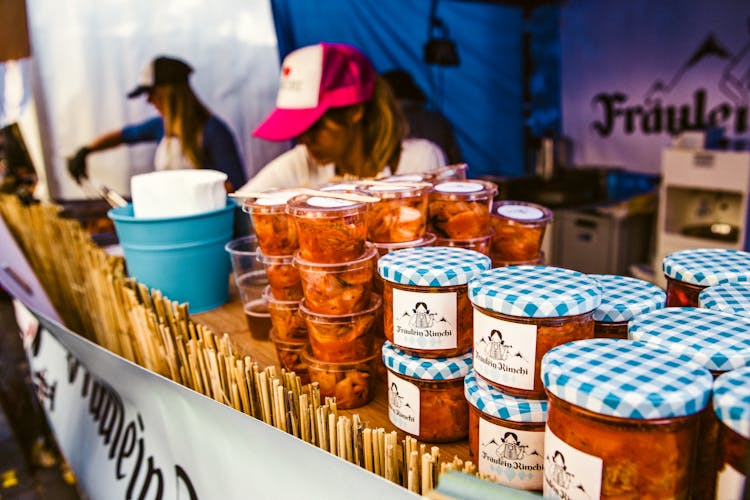 Woman Selling Canned Food On Display Table