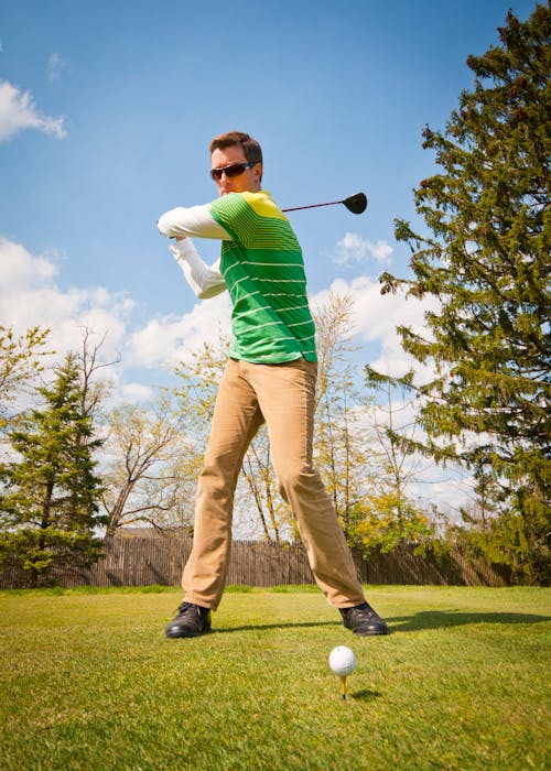 Man in Green and White Stripes Long Sleeve Shirt Holding Black Golf Club