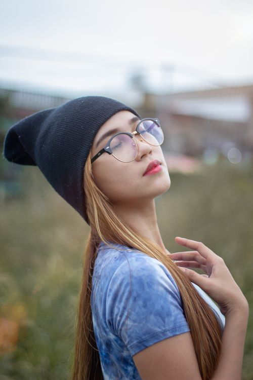 Free Serene portrait of an Asian woman with glasses and a knit cap, eyes closed. Stock Photo