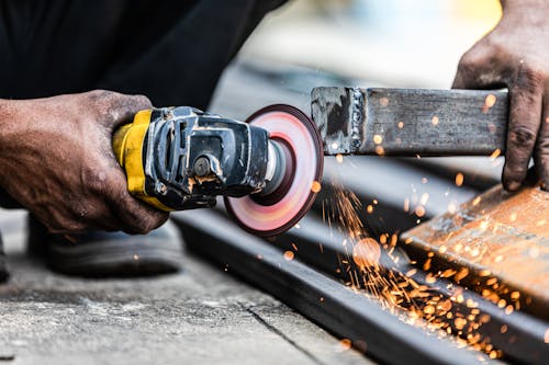 A Person Using an Angle Grinder on a Metal Bar