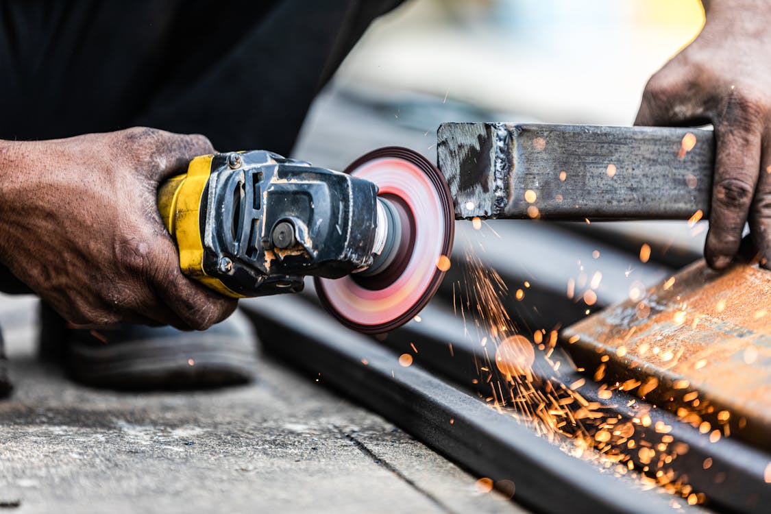 A Person Using an Angle Grinder on a Metal Bar
