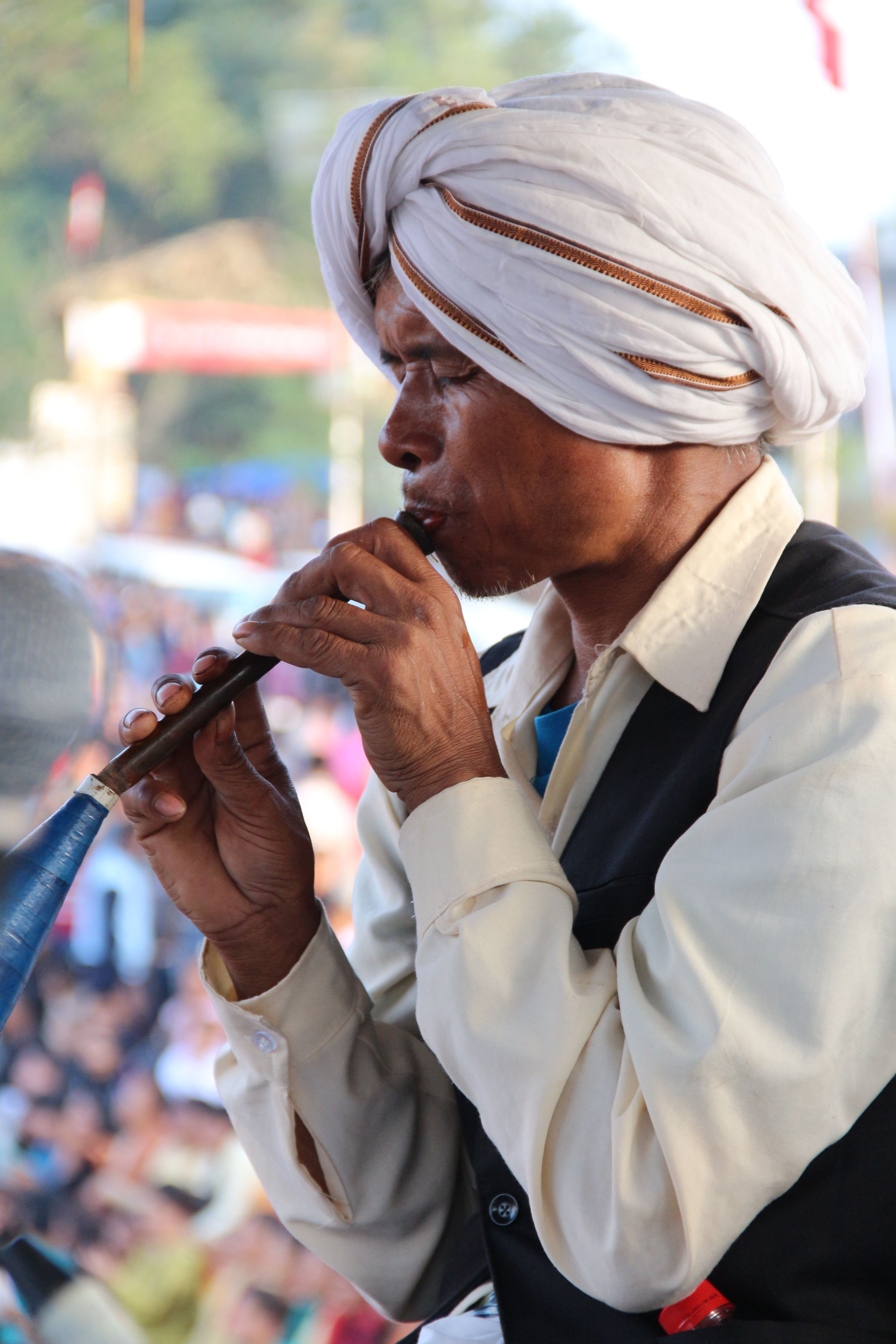 A man in traditional attire playing a wind instrument at a cultural festival.