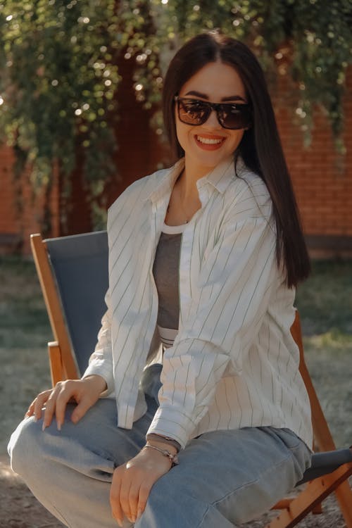 Woman in White and Gray Striped Blazer Sitting on Brown Wooden Chair