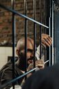 Man in Black Jacket Leaning on Black Metal Fence