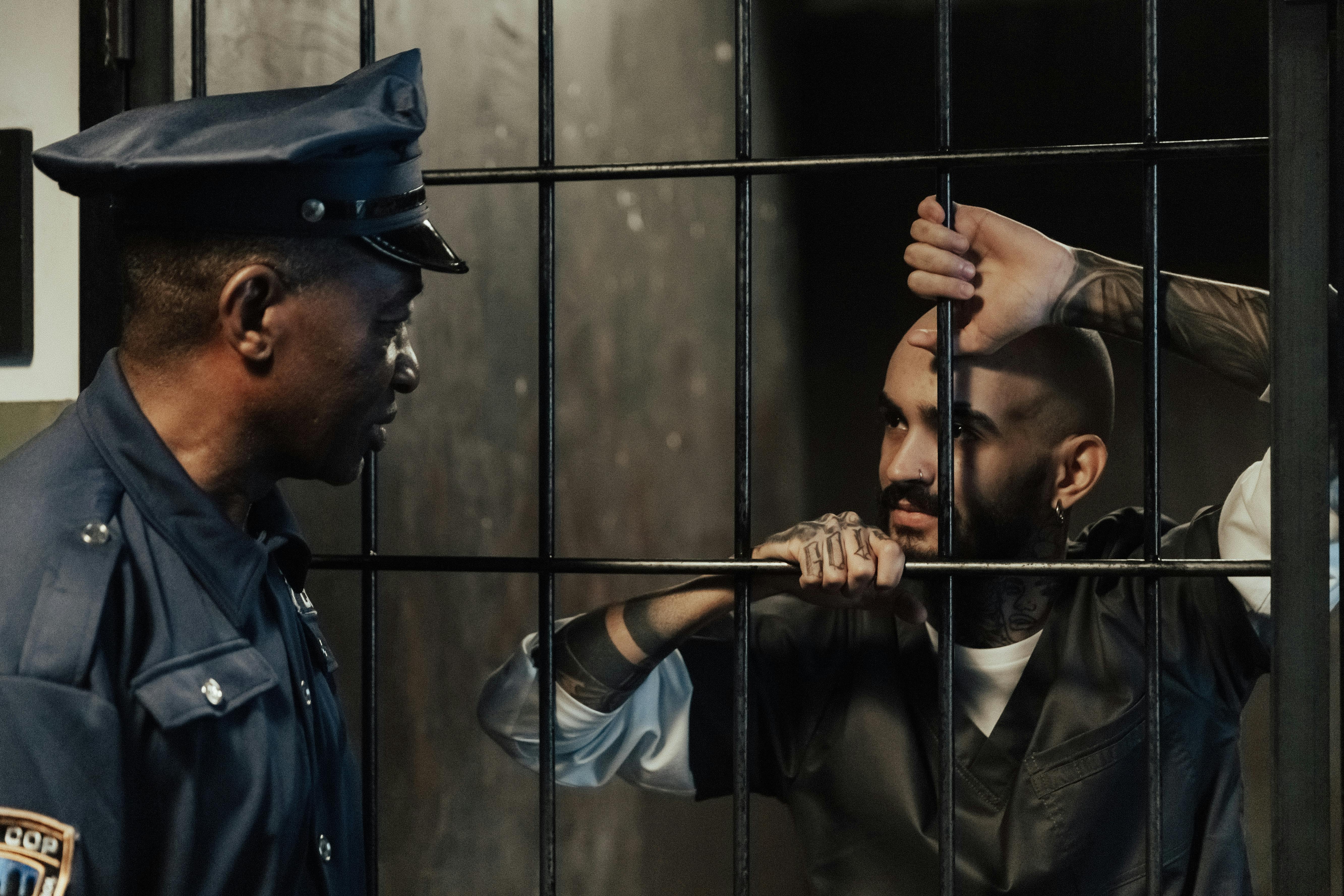 policeman near a man in a prison cell