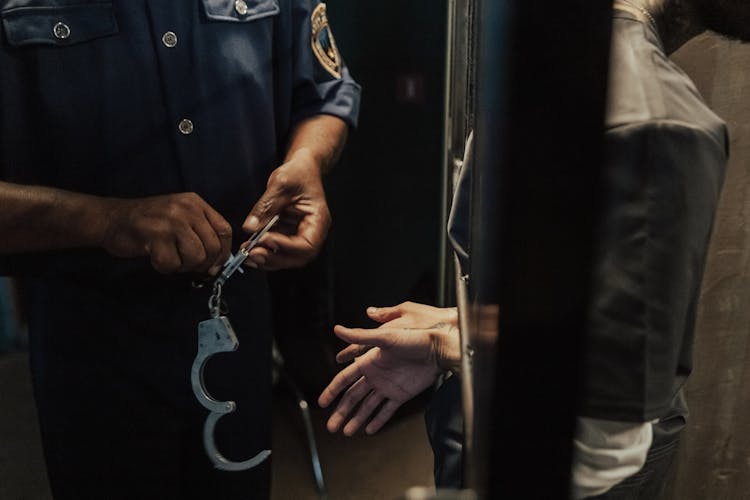 Policeman With Handcuffs With Prisoner In Jail