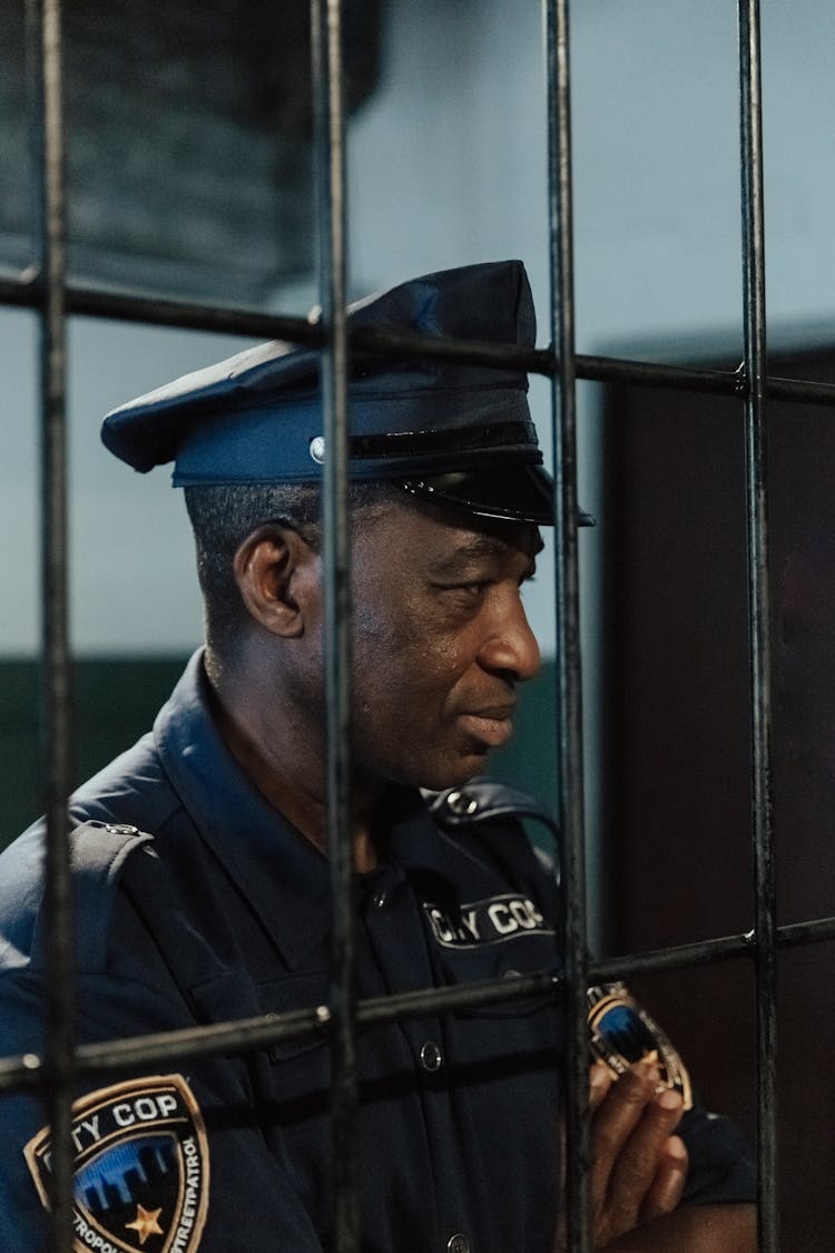 Policeman Looking Through Metal Bars In Jail