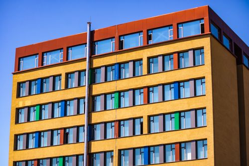 Free Vibrant modern building with colorful glass windows and geometric design against a clear blue sky. Stock Photo