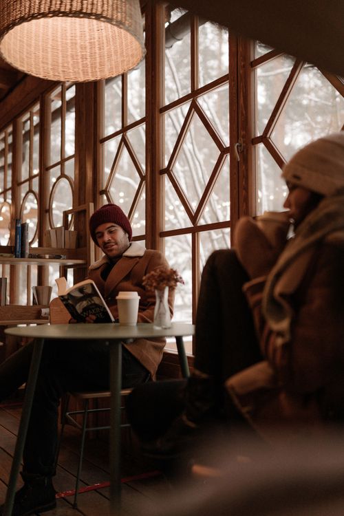 Free A couple enjoying leisurely time in a cozy café with winter scenery outside. Stock Photo