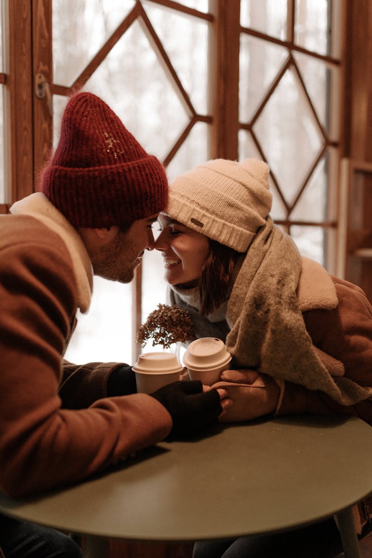 Man And Woman Smiling By Table And Touching With Noses