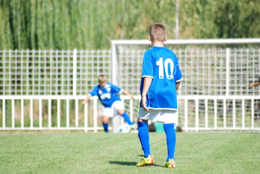 Young boys playing soccer in blue jerseys on a sunny day.