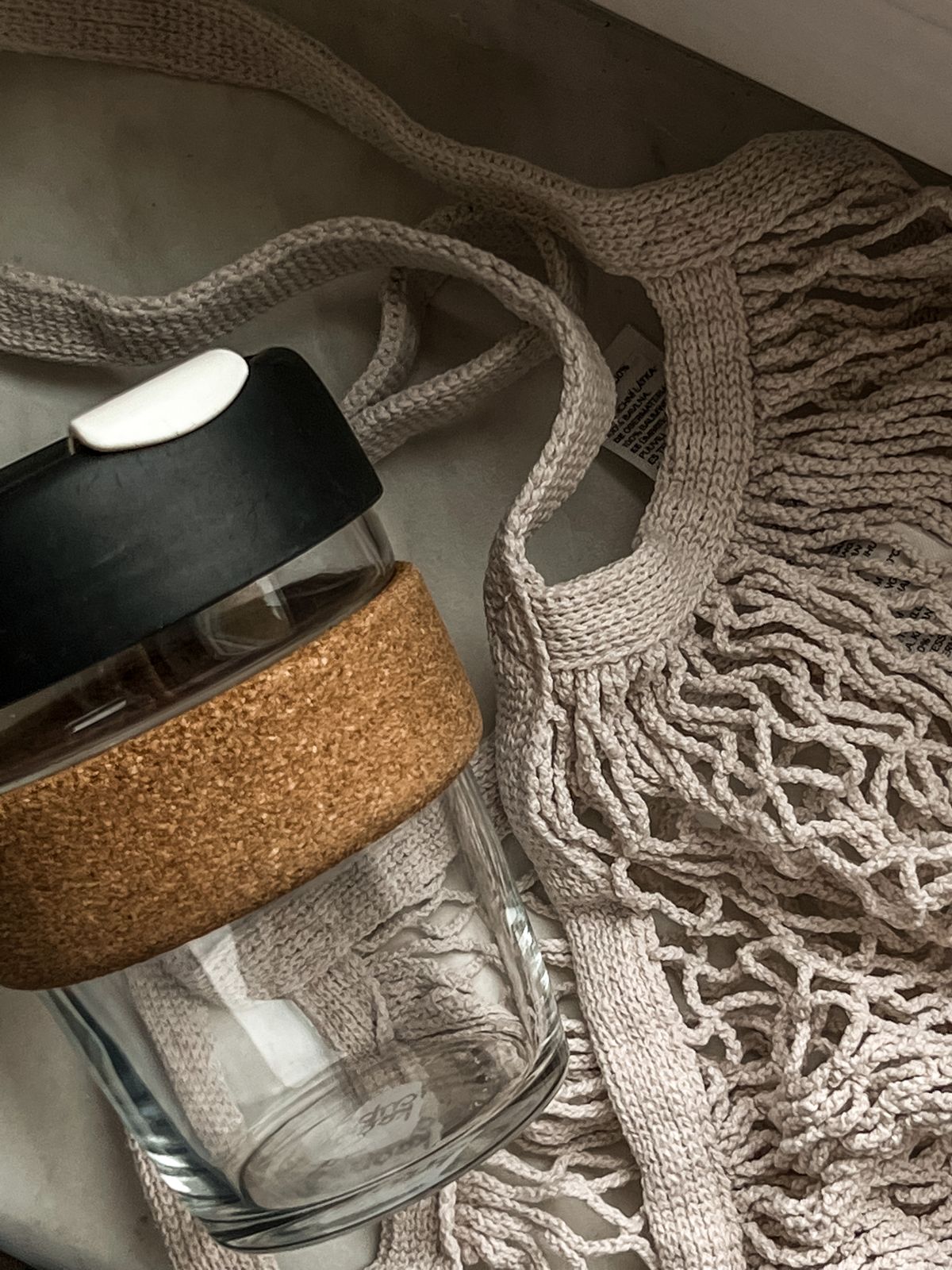 Tumbler kaca dengan tutup gabus dan tas mesh reusable sebagai alternatif plastik sekali pakai