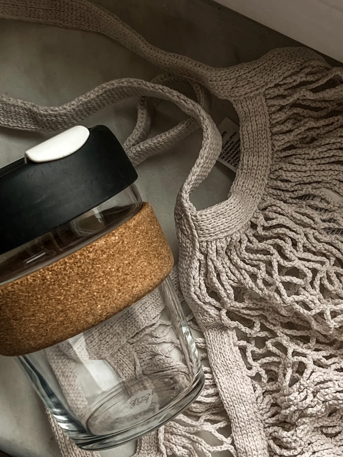 Tumbler kaca dengan tutup gabus dan tas mesh reusable sebagai alternatif plastik sekali pakai