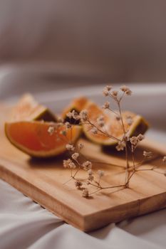 Orange slices and dried flowers on a wooden board creating a warm, artistic still life.