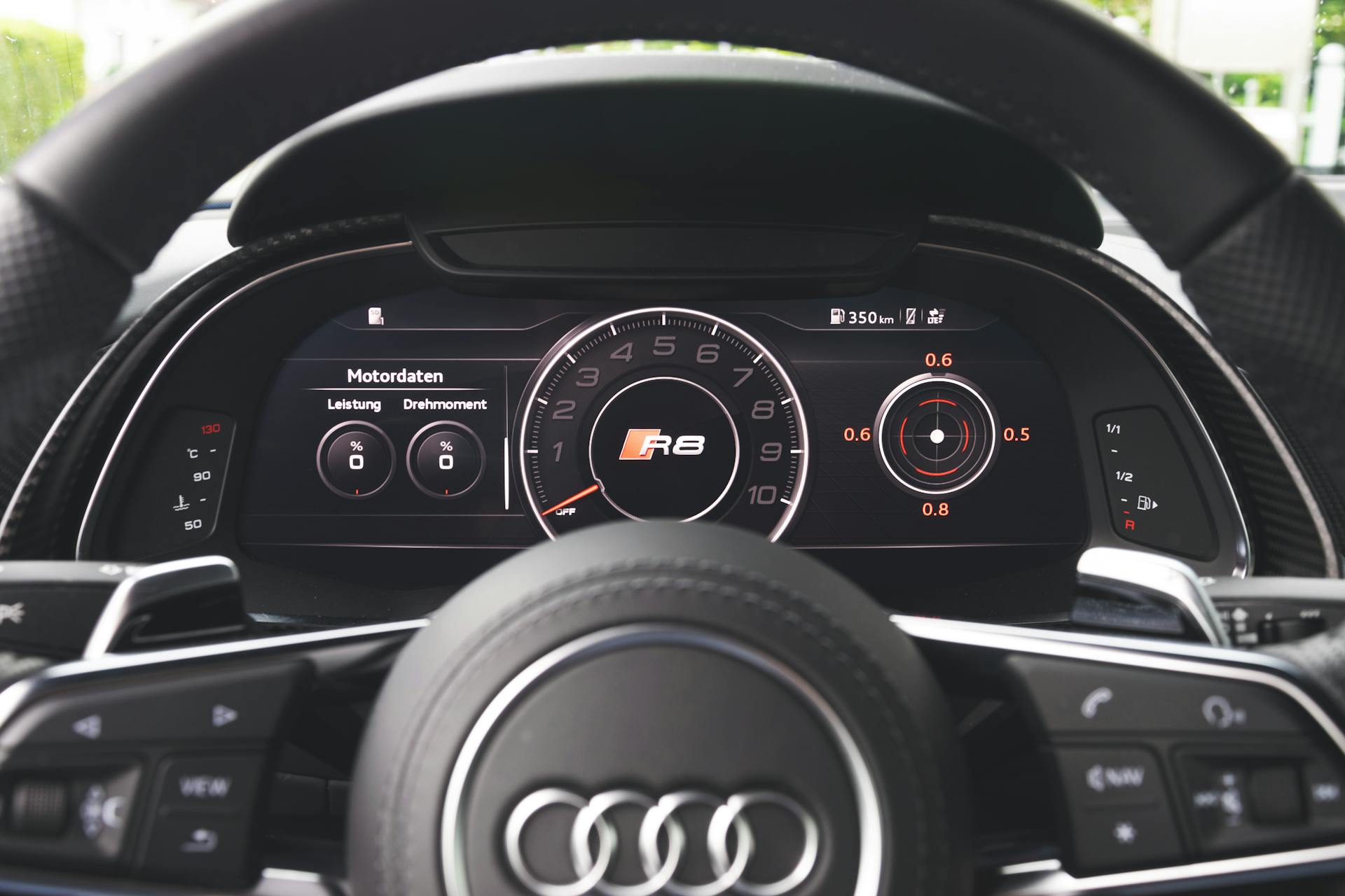 Interior view of Audi R8 dashboard featuring digital gauges and steering wheel close-up.