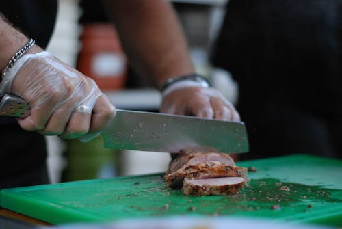 Close-up of a Person Cutting Grilled Meat on a Chopping Board