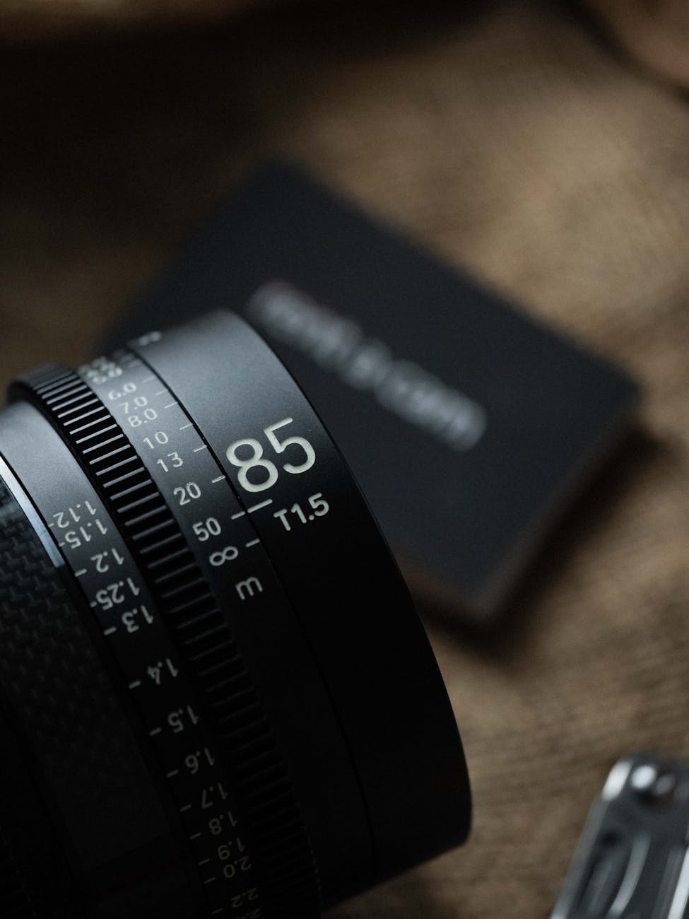 A detailed close-up of an 85mm camera lens showing aperture and focus numbers, set against a textured background.