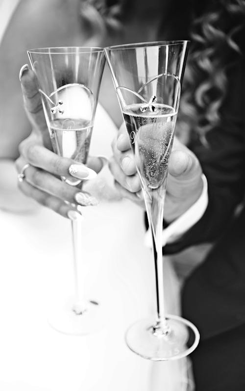 Grayscale Photo of People's Hands Holding Glasses of Champagne