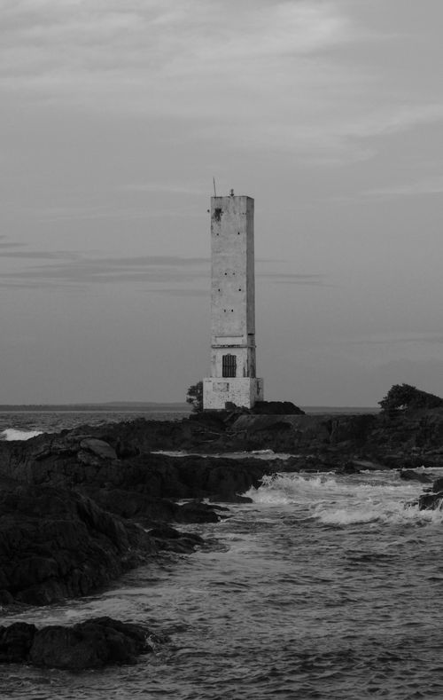 Free Black and white image of a lighthouse standing on a rocky coastline in Itacaré, Brazil. Stock Photo