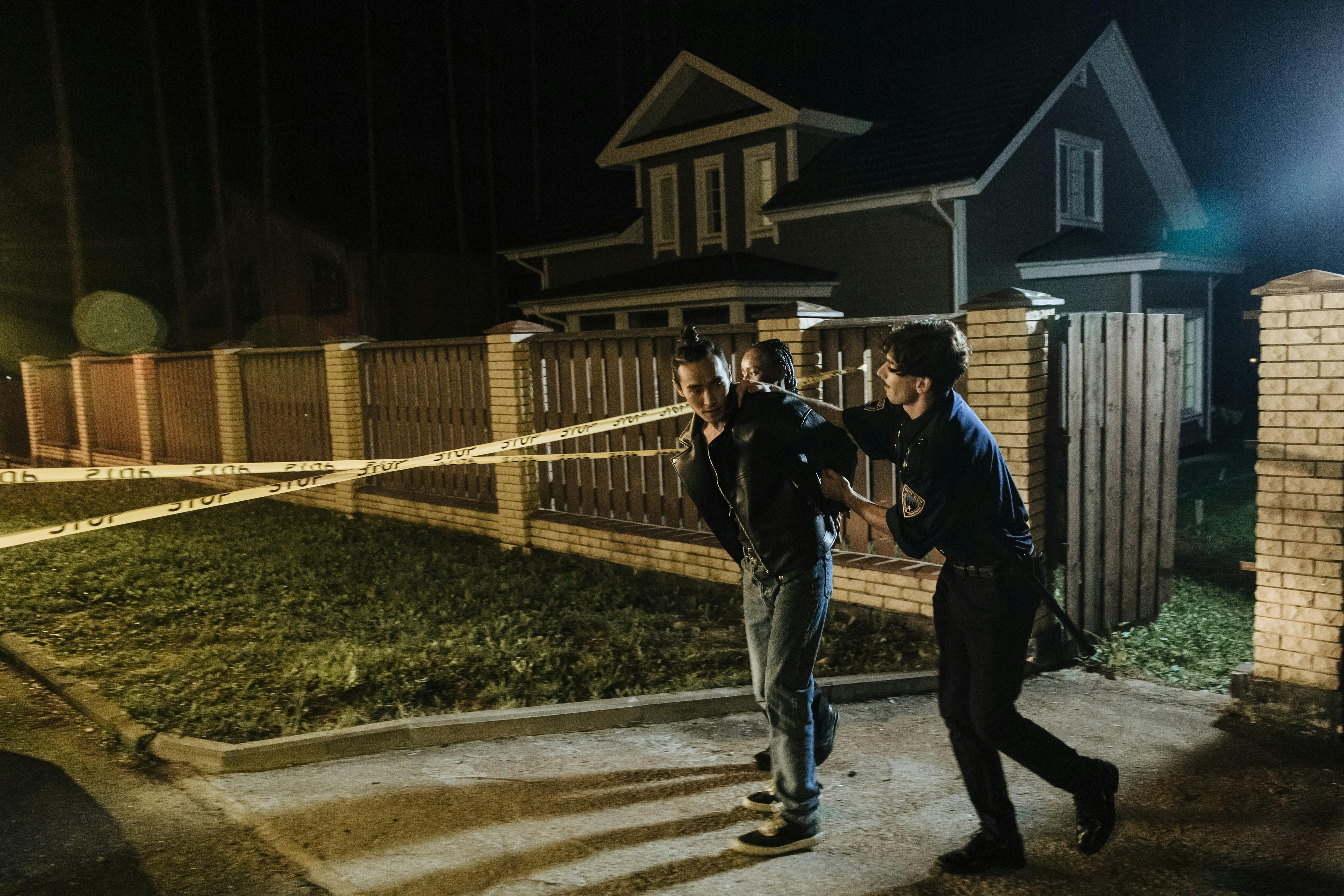 a man in blue uniform arresting man in black jacket