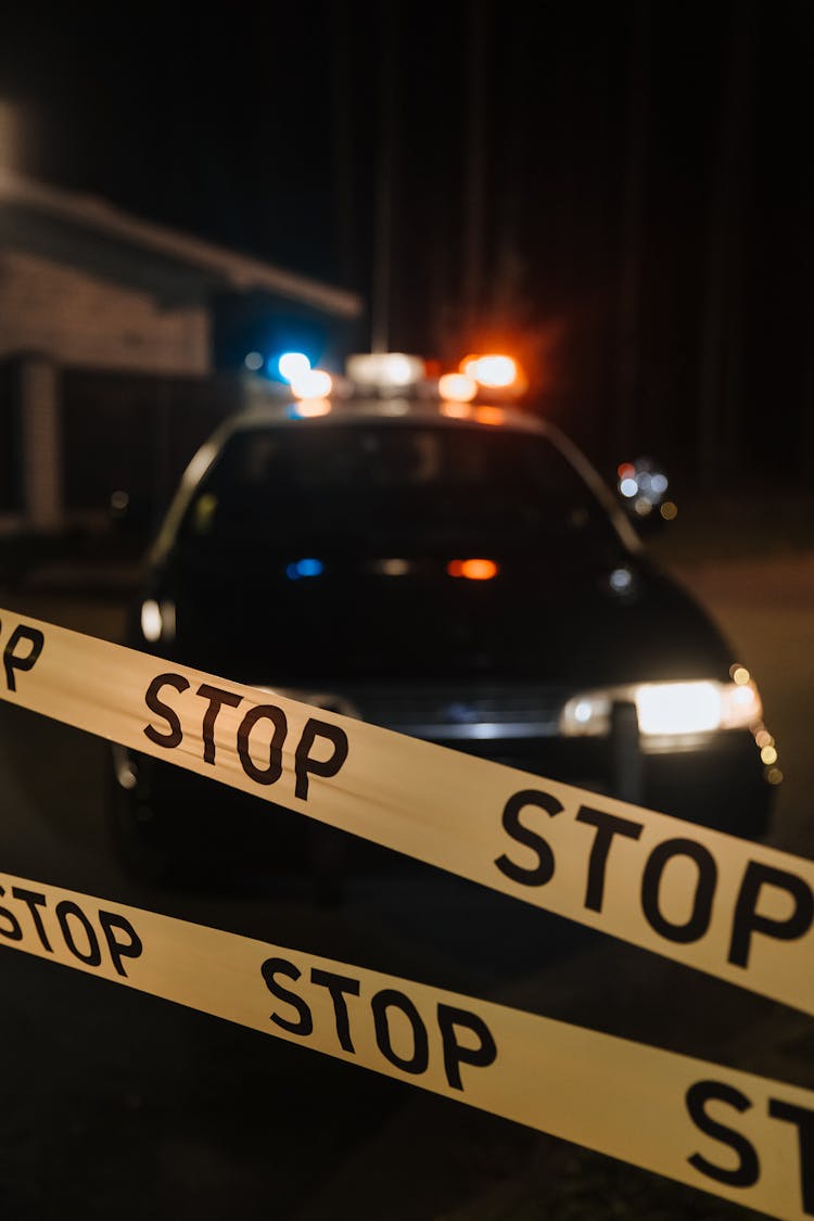 Yellow Crime Tape Against Police Car