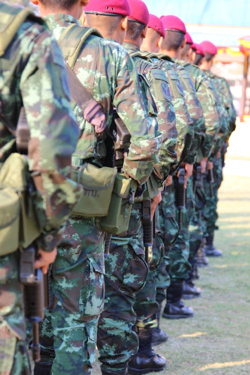 Gratis Persone Che Indossano Tuta Militare Mimetica Verde E Marrone Mentre Stanno Tenendo I Fucili Foto a disposizione