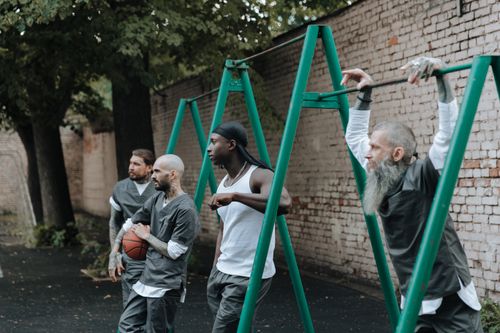 Free Four men stand in an outdoor yard with exercise equipment, one holding a basketball. Stock Photo