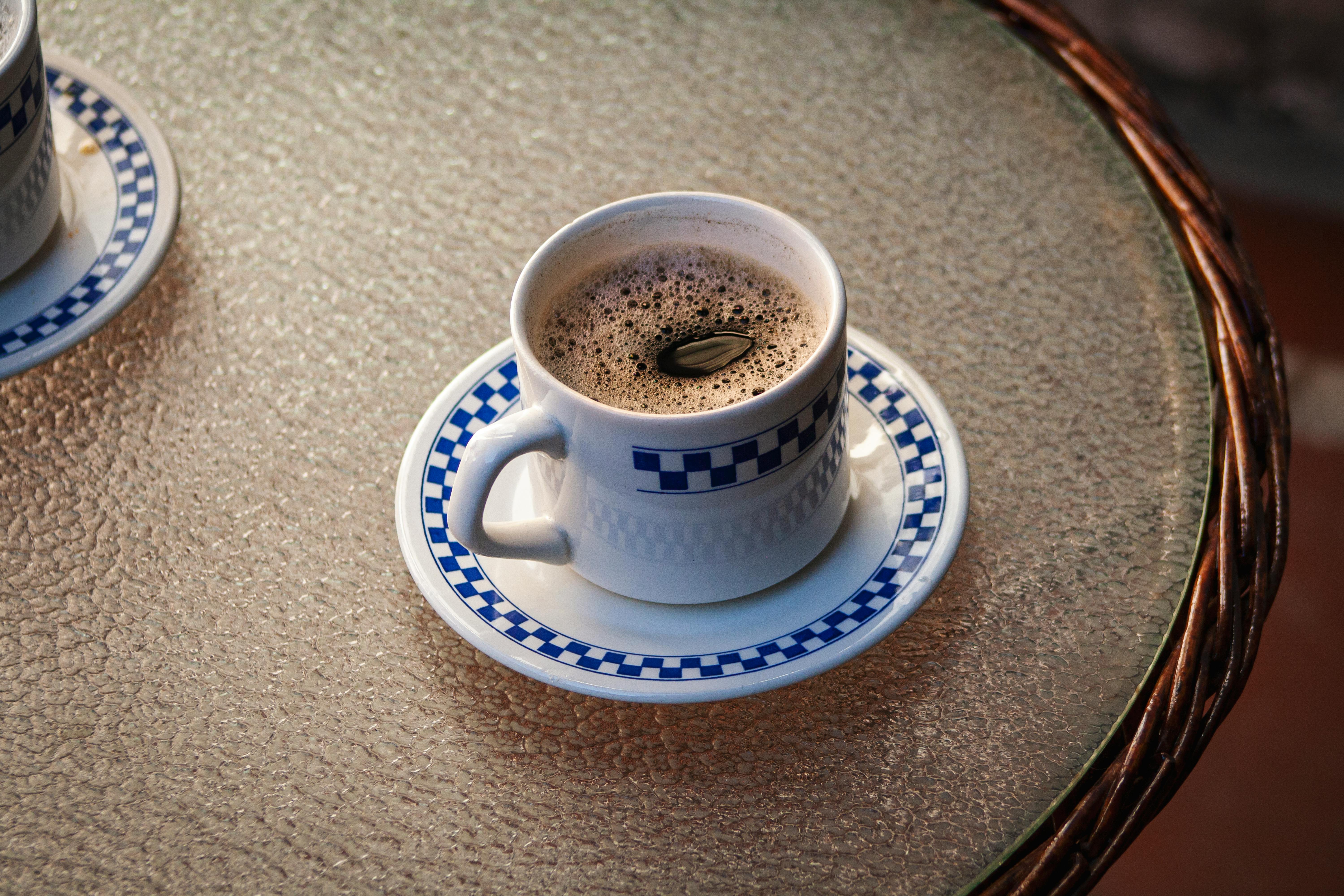 photo of a white and blue cup with black coffee