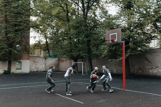 Inmates play a basketball game on an outdoor prison court surrounded by trees.