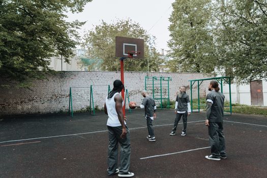 Men playing basketball on an outdoor court surrounded by greenery.