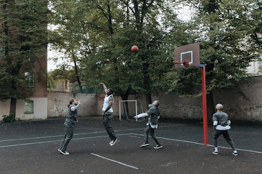 Group of inmates engaged in a basketball game on an outdoor court.
