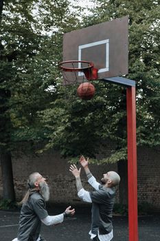 Two men playing basketball in a prison yard under outdoor conditions.