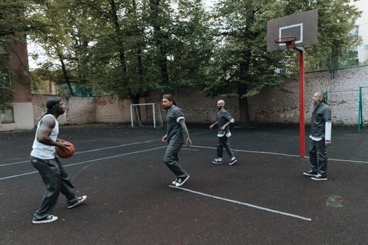 Inmates play basketball on a prison court, showcasing camaraderie and sportsmanship.