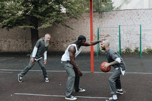 Men playing basketball in a prison yard, showcasing teamwork and recreation in confinement.