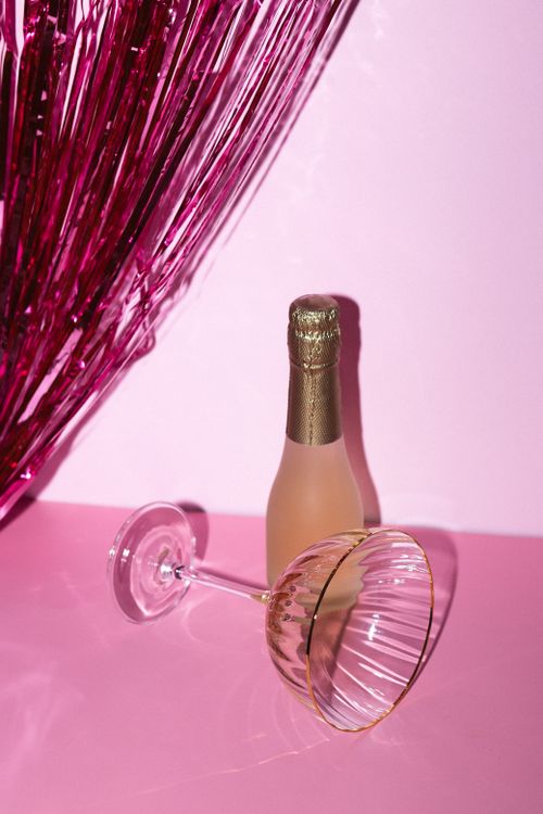 Free Elegant champagne bottle and glass on a vibrant pink background setting. Stock Photo