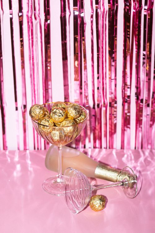 Free Elegantly arranged champagne and chocolates on a pink table for a festive celebration. Stock Photo