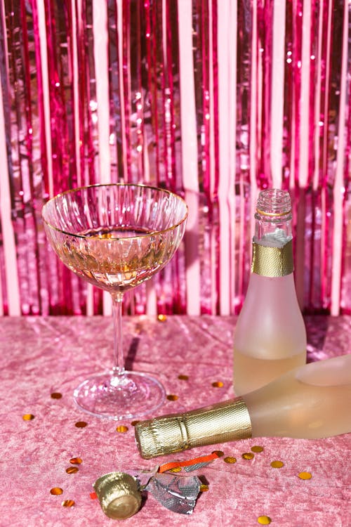 Champagne Bottles and Wineglass on Pink Background