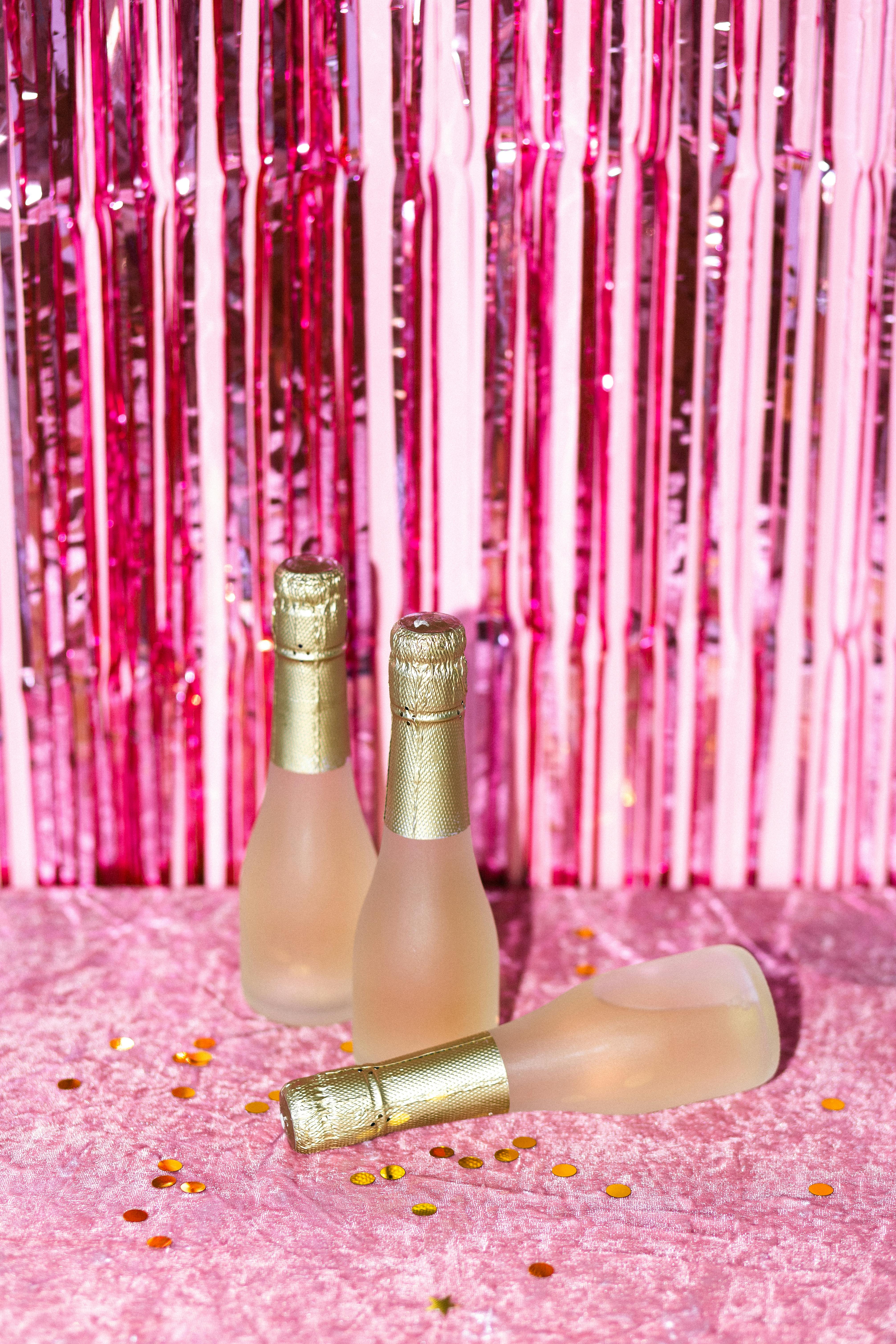 champagne bottles on pink surface with gold confetti