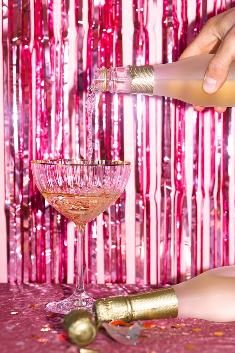 Person Pouring Champagne On Coupe Glass 