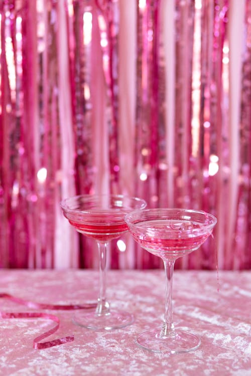 Cocktail Glasses with Pink Liquor Standing on Pink Background 