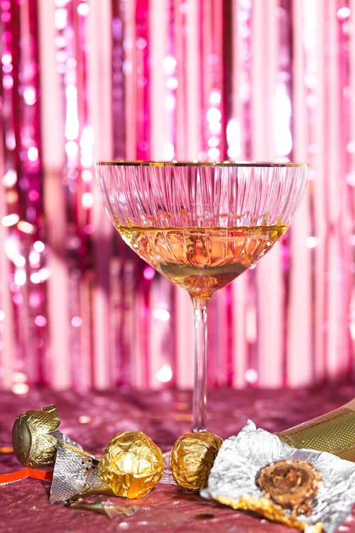 Close-up of a Cocktail Glass and Leftover Chocolates against Pink Background