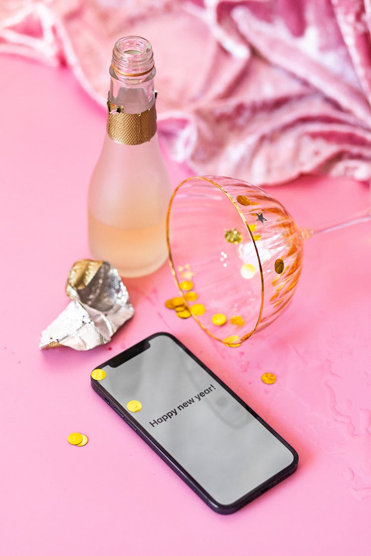 Smartphone And Gold Confetti On Pink Surface